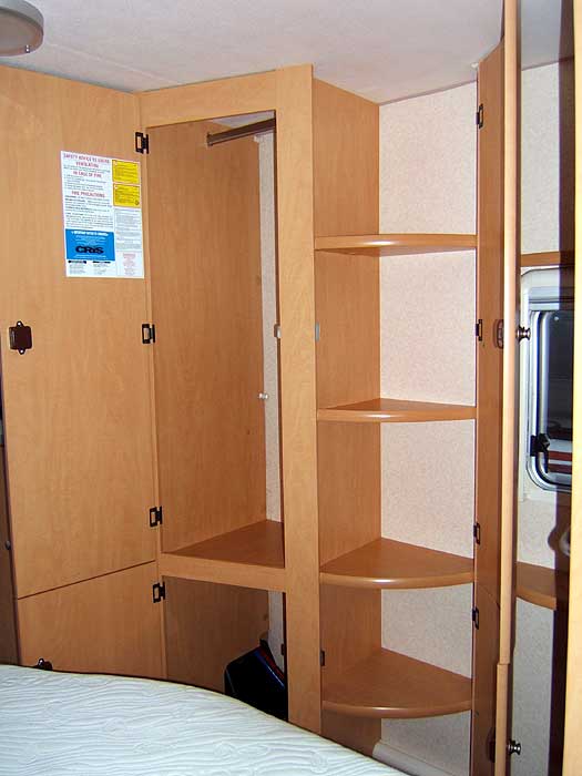 This wardrobe style cupboard with hanging rail and shelf units is tucked into the corner of the bedroom.
